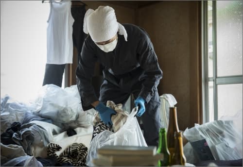 ごみ屋敷を男性が片付けている様子